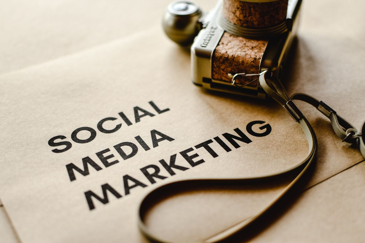 Gros plan d’un appareil photo posé sur du papier brun avec le texte Social Media Marketing, mettant en avant les thèmes du marketing digital.